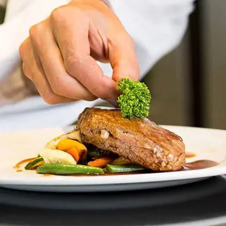 Sanford Estates Chef Created Meals, chef garnishing a plate.